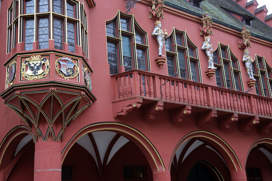Außenfassade historisches Kaufhaus mit roter Farbe, Rundbögen und goldenen verzierten Fensterelementen